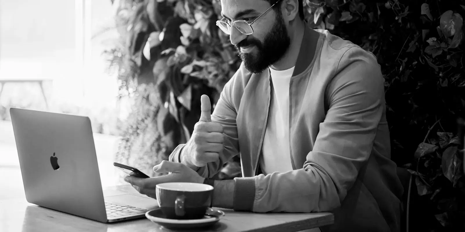 Alguien está trabajando en una computadora portátil con un café en la mesa cerca de una pared verde